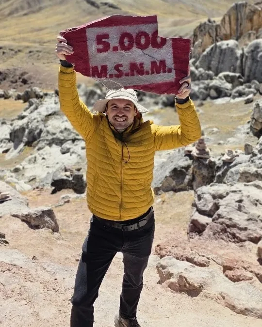 Ryan Frazier smiling and holding up a 5,000-meter elevation sign in the Peruvian Andes